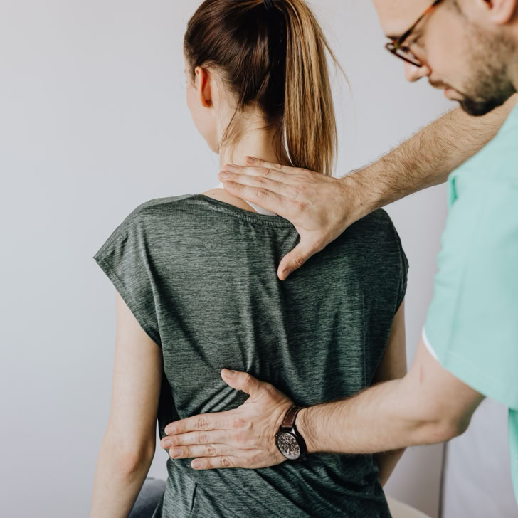 Ein Chiropraktiker untersucht die Wirbelsäule eines Patienten in einer klinischen Umgebung. Fokus auf Gesundheitsversorgung und Rehabilitation.
